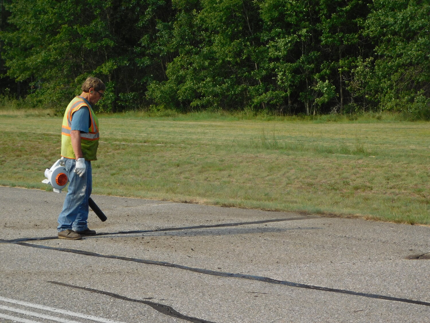 County and road commission workers take on the task of blowing out the runway cracks Monday morning, in preparation for the sealing work to be done the following day.
